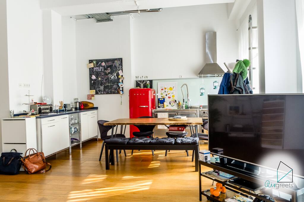 The light-flooded and spacious room offers an industrial kitchen and a dining area next to the living area.
