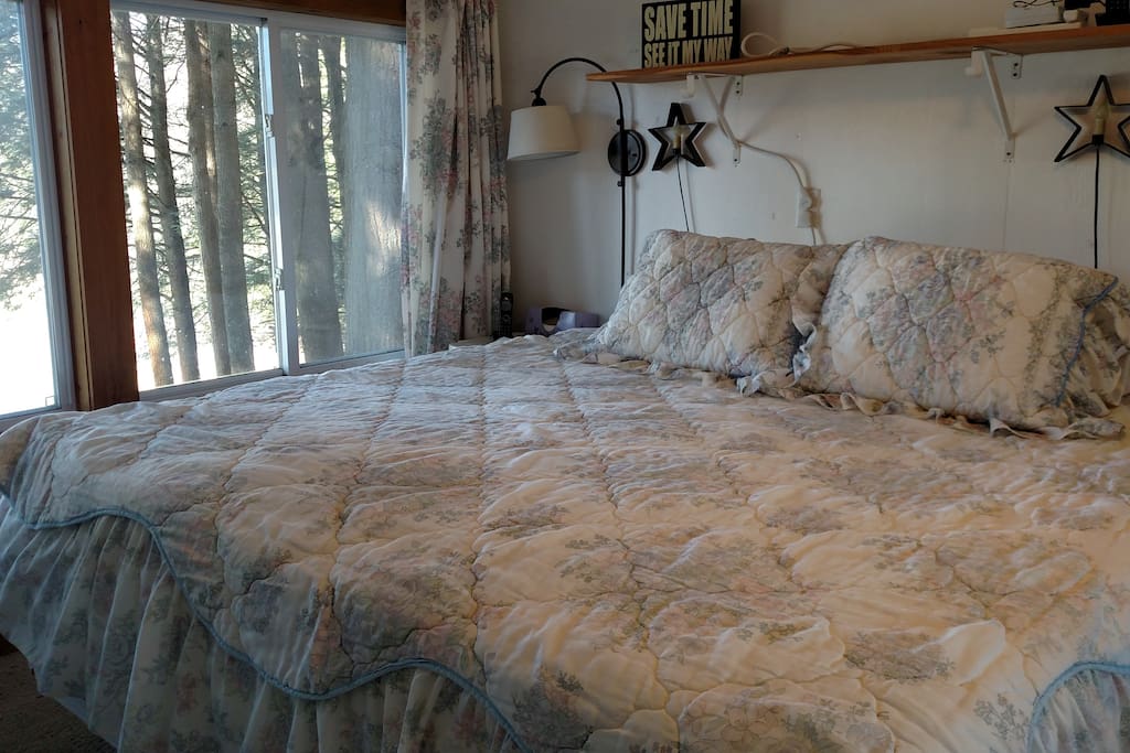 Partial view of bedroom with adjustable king-sized bed and wall-to-wall mirrored closet overlooking the river and field across the way