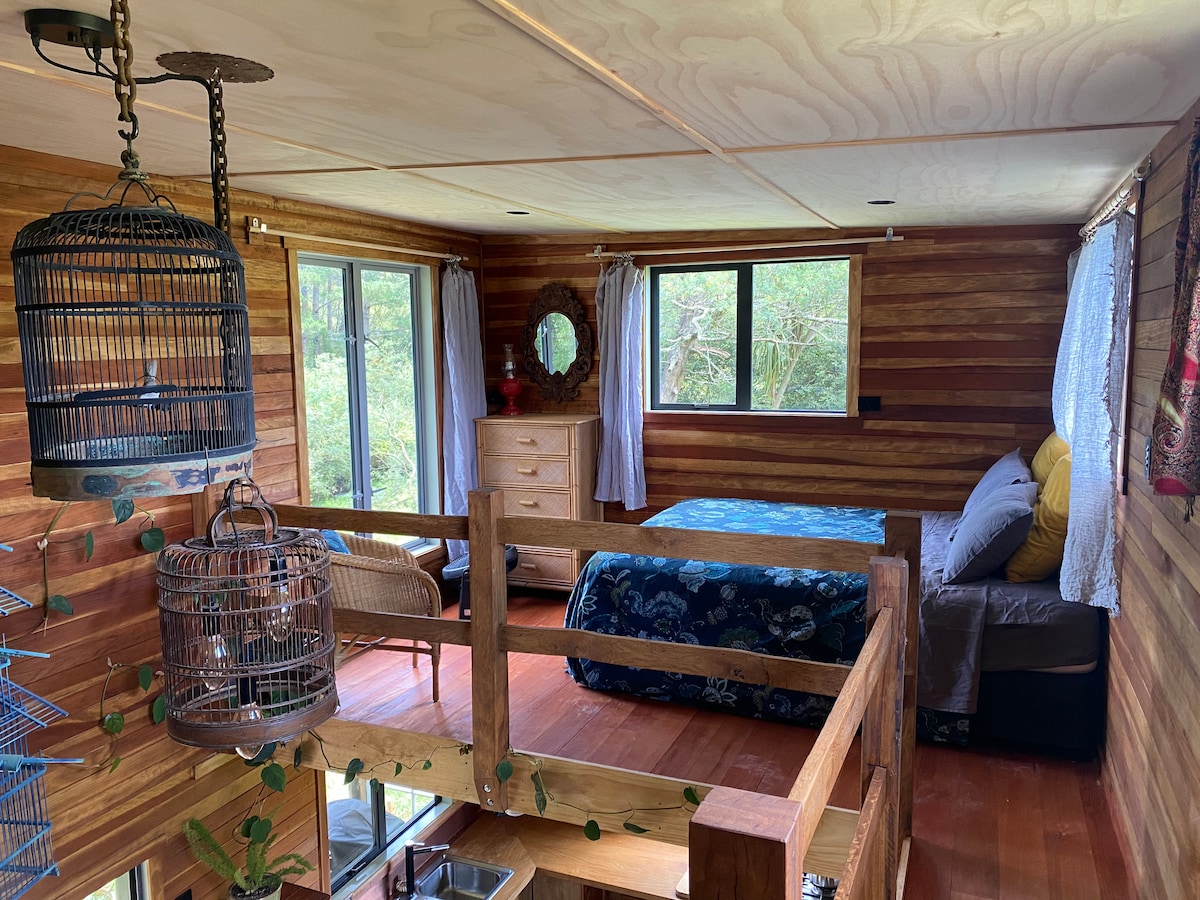 Queen bed sharing the upstairs space with a double bed on the other side of the walkway, no walls separating them. at Lone Oak Eco Cabin in Okoroire