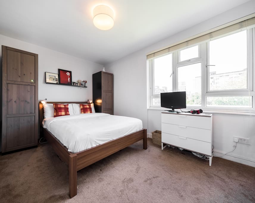 Welcome to our home! This spacious bedroom has a TV and a comfortable double bed.