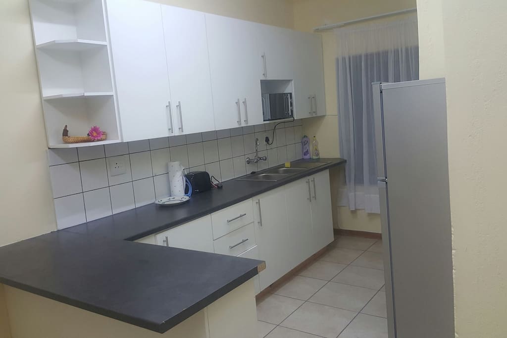Spacious kitchen with stove, fridge, microwave, kettle, toaster and basic kitchen cutlery.