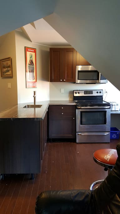 Stove, toaster, coffee maker microwave, fridge, bar area, dishes, pots, basic utensils.