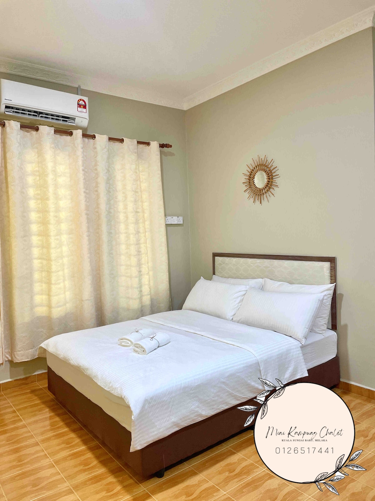 A cozy sleeping area is presented with a queen bed, fresh linens, and a soft rolled towel placed neatly. Natural light filters through sheer curtains, illuminating the space. A wall-mounted air conditioning unit and a decorative mirror add a functional and stylish touch.