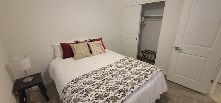 Chambre #3. Matelas Sealy Queen Size flambant neuf. Stand de nuit avec lampe (y compris port de recharge USB). Le placard comprend un porte-bagages et des cintres.
