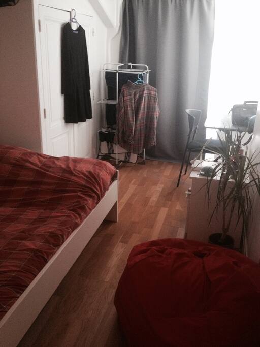 Chambre lumineuse avec grand lit et bureau.