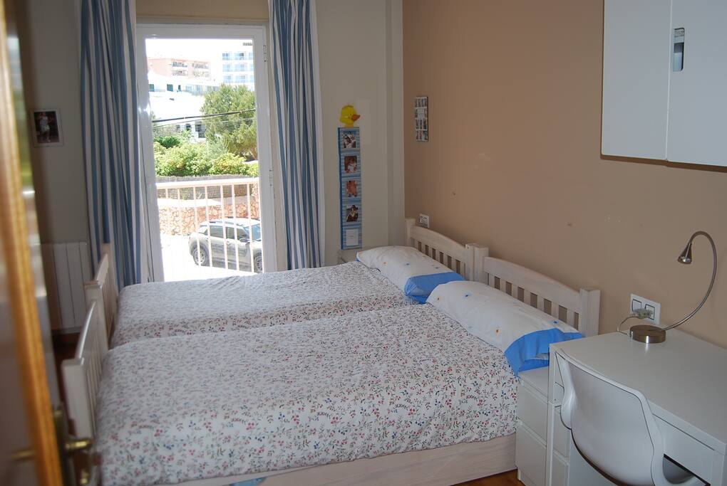 Habitación con tres camas, dos armarios y un balcón privado con vistas al mar