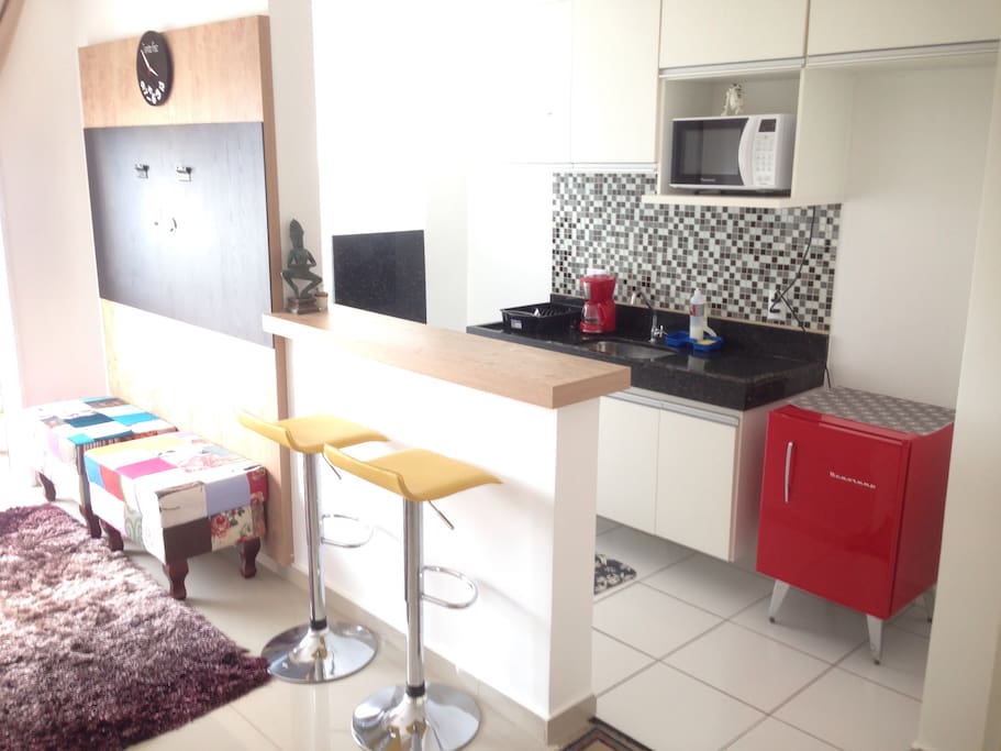 Cozinha Americana com armários, microondas, frigobar, cafeteira elétrica e sanduicheira elétrica.