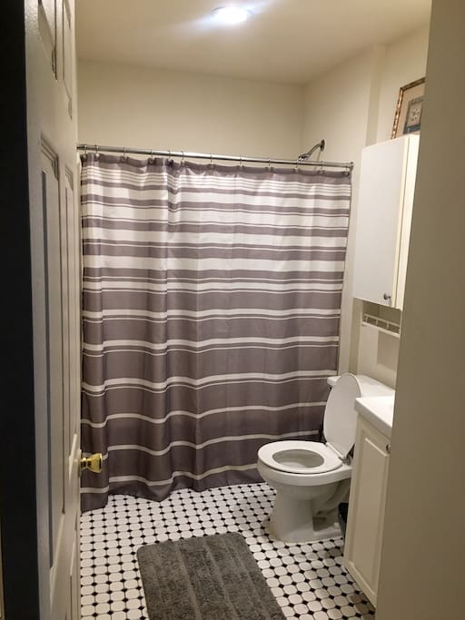 Clean bathroom with tub/shower and full length mirror.