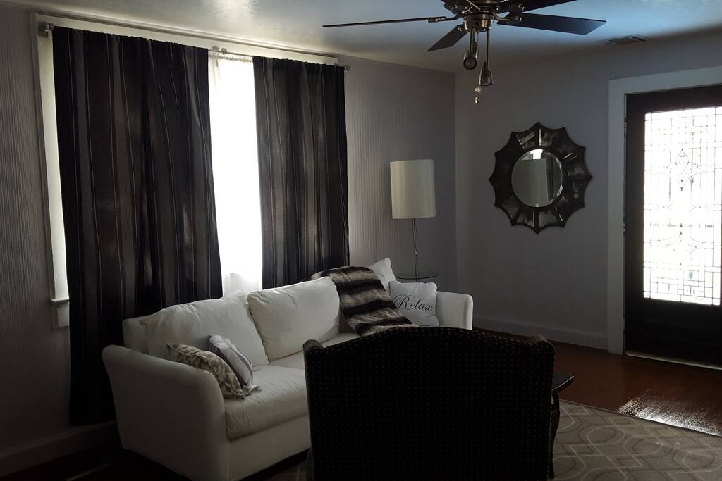 Living room has sofa, wing back chair and desk. It is tastefully furnished.