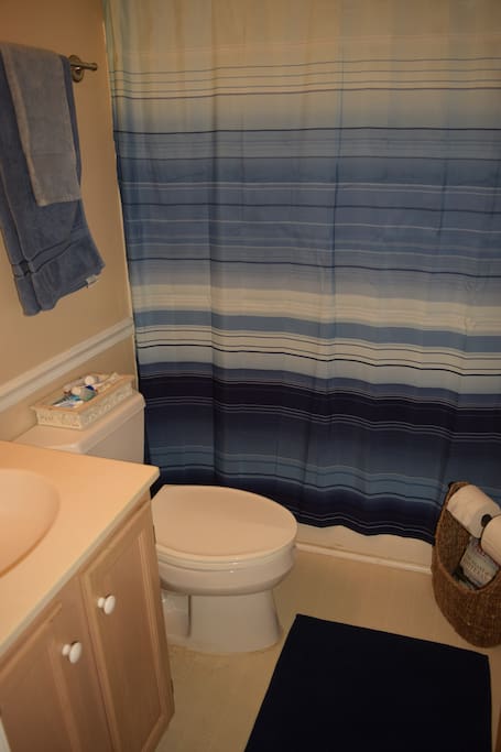 Clean, private bathroom with toilet, sink, mirror, shower/tub and towels.