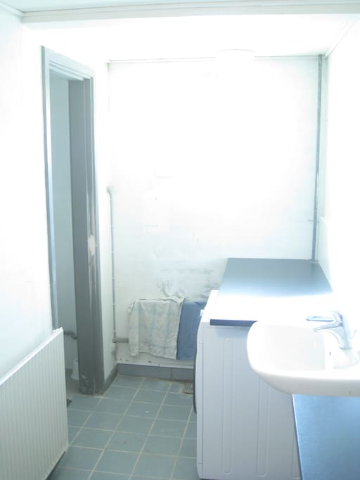 Bad, bruserum, bordplade og vaskemaskine.
3 personer deler badet
