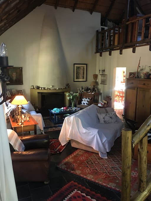 THE SITTING ROOM WITH A BIG FIREPLACE. THE T.V.IS TUCKED UNDER THE STAIRS ON THE RIGHT.