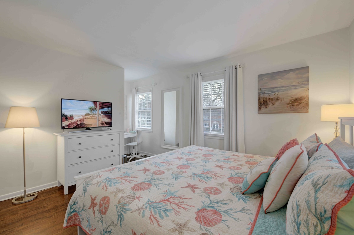 חדר שינה ראשי עם מיטת קינג סייז ומכונת כביסה/מייבש כביסה , טלוויזיה ושולחן עבודה