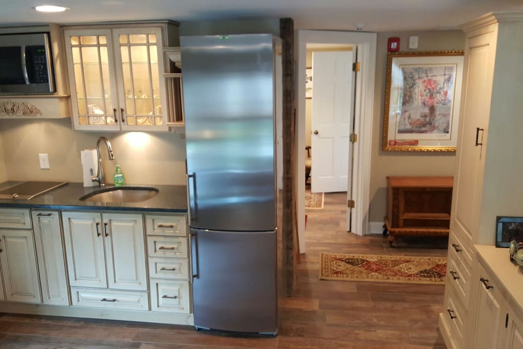 Kitchen and hallway areas from the living room. Custom made wooden dresser on the right and custom refrigerator.