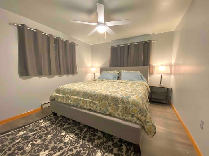 Chumba cha kulala cha ghorofa kuu chenye kitanda aina ya king na mapazia ya kuzuia mwanga. Kidhibiti cha joto cha umeme ndani ya chumba; hakuna AC lakini feni ya dari imejumuishwa.