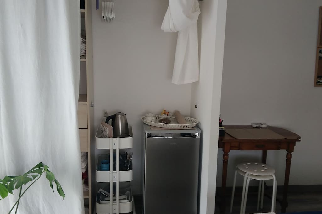 Chambre privée ; frigo, de quoi préparer thé et café, vaisselle à disposition dans petite desserte. Petite penderie au dessus avec cintre et derrière le rideau une étagère et un tirroire.