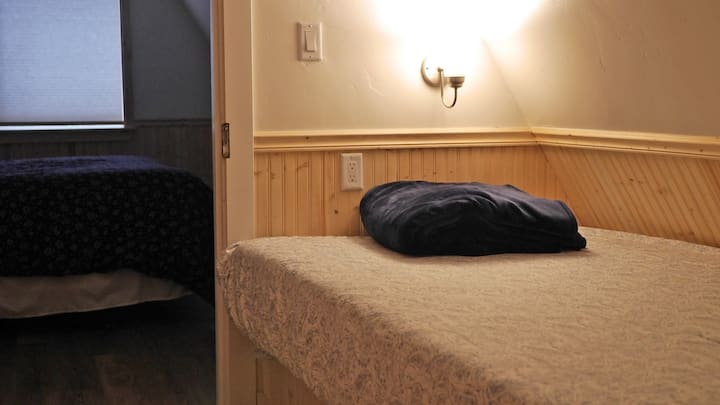 Целосен кревет во „спална соба“ 4 со врати што се затвораат, во непосредна близина на спална соба со прозорец. Повеќето гости ја оставаат вратата помеѓу спалните соби отворена.