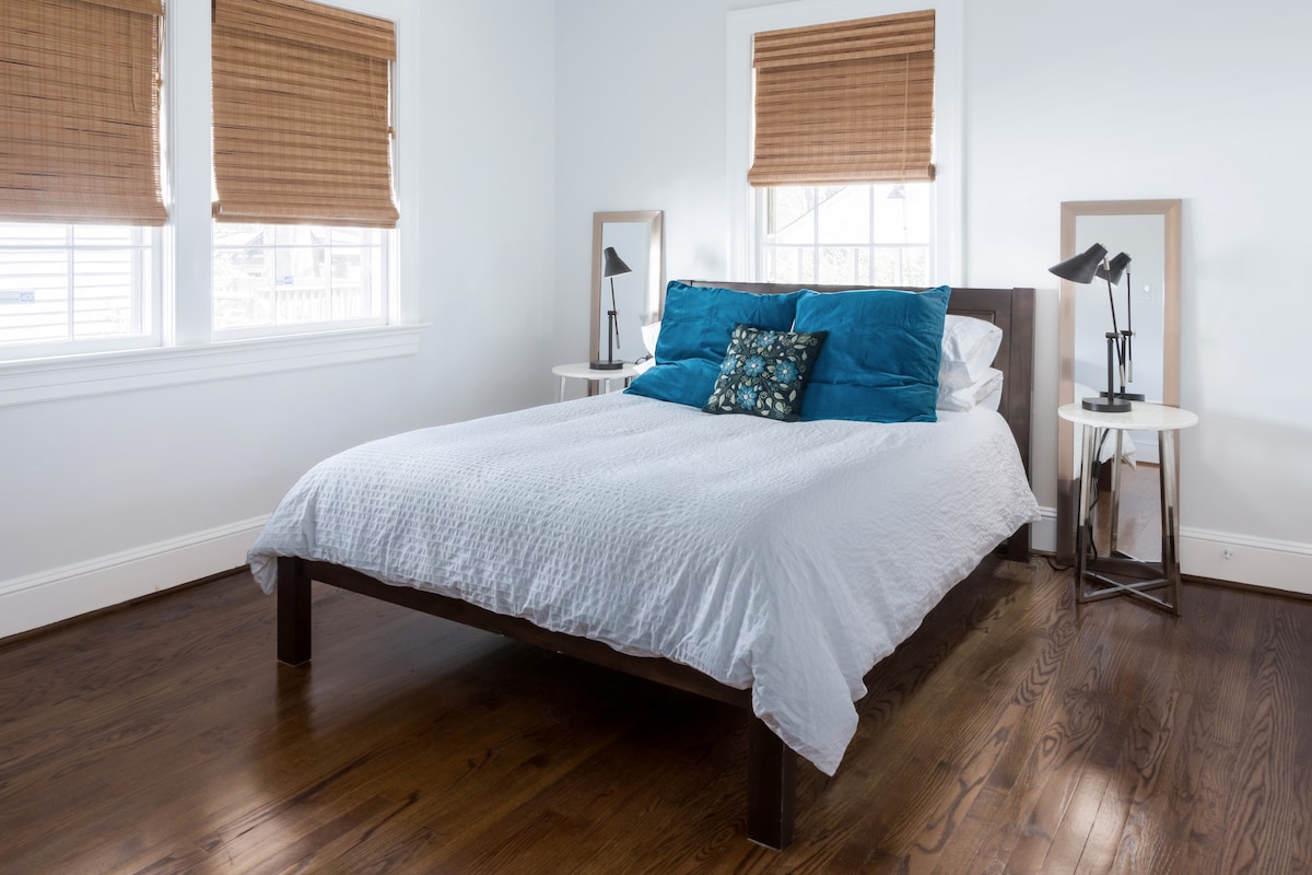 ห้องนอนใหญ่พร้อมเตียงขนาดควีนไซส์และม่านบังแสงบนหน้าต่างทุกบาน