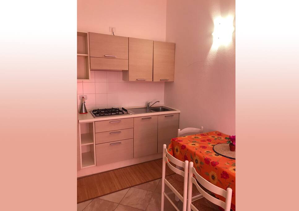 Salone con cucina a vista e divano letto.