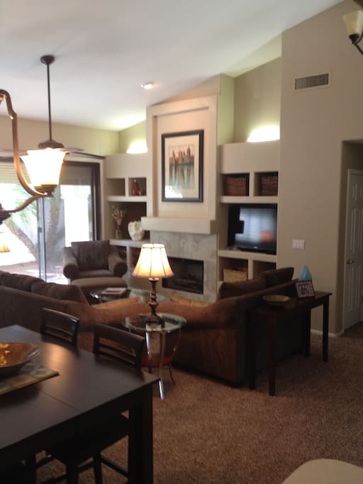 Standing near the kitchen looking into the living room. Full length, steel, security shades cover all the rear facing windows/doors.
