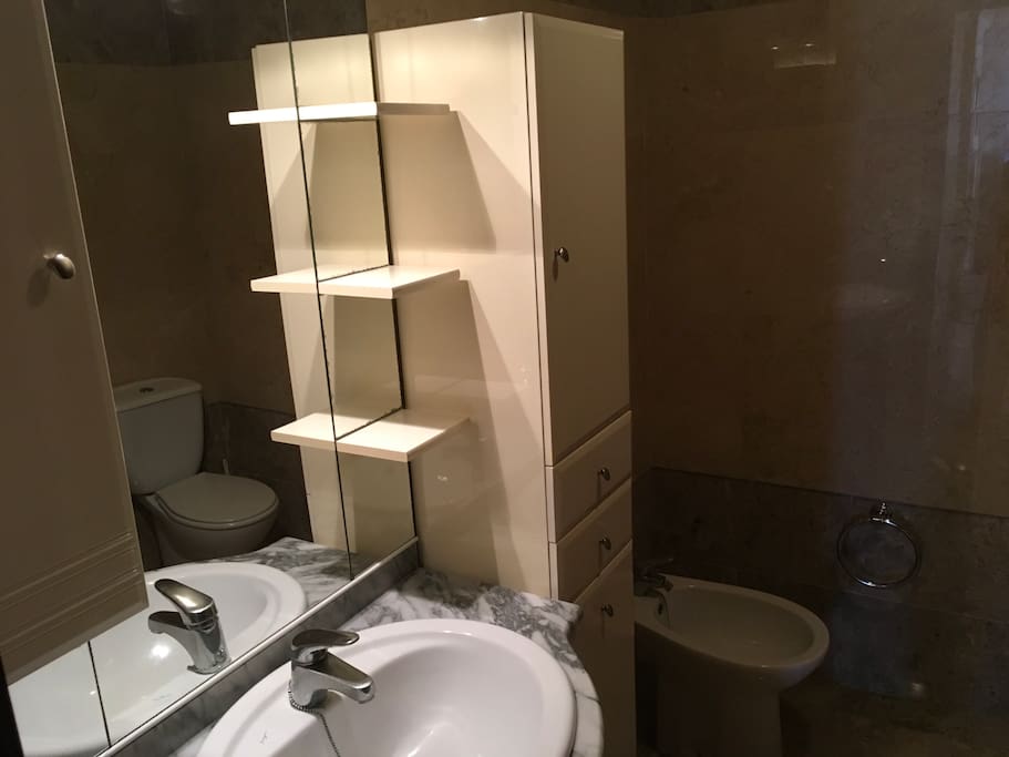 Baño interior con ducha , bidé, wc, y lavamanos , con toallas y papel , champú , papeleras, secador y espacio para cosas de aseo .