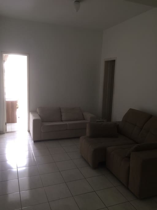 Sala ampla com dois sofás sendo um retrátil pode ser usado como sofá cama