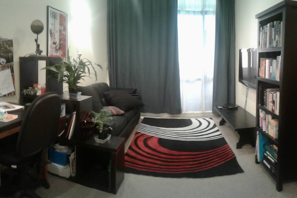 lounge room with couch, large wall mounted flat screen TV, BluRay and Netflix, and balcony.