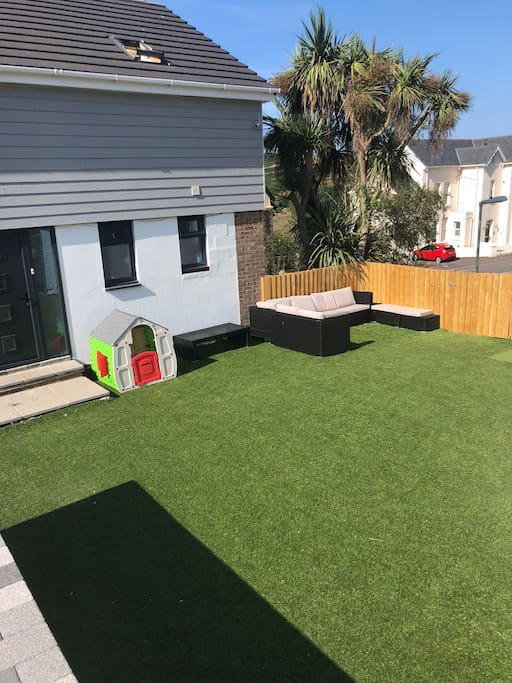 Spacious astroturfed front garden with seating areas