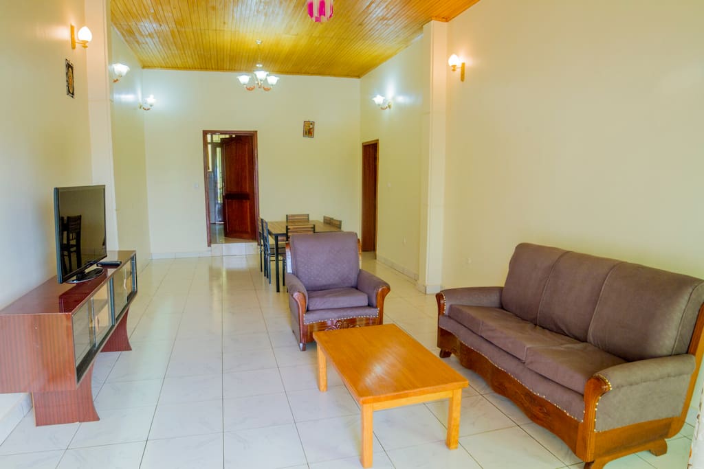 Living room sofas, coffee table, TV on tv stand and view of the dining table
