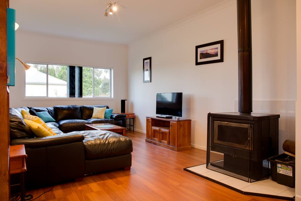 Lounge room with 8 seater leather lounge and slow combustion fire.