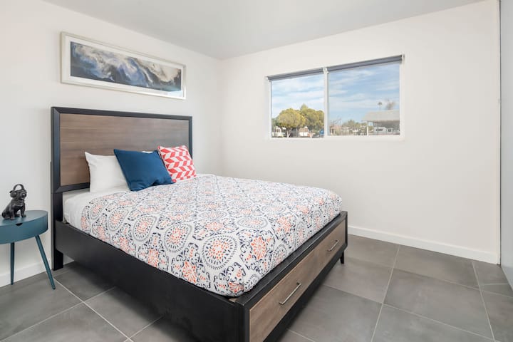 חדר שינה לאורחים עם מיטה זוגית, ארון גדול וטלוויזיה חכמה המותקנת על הקיר.  תריסים מושכים ומתגלגלים מעניקים לכם פרטיות בלילה ואור שמש בהיר במהלך היום. 