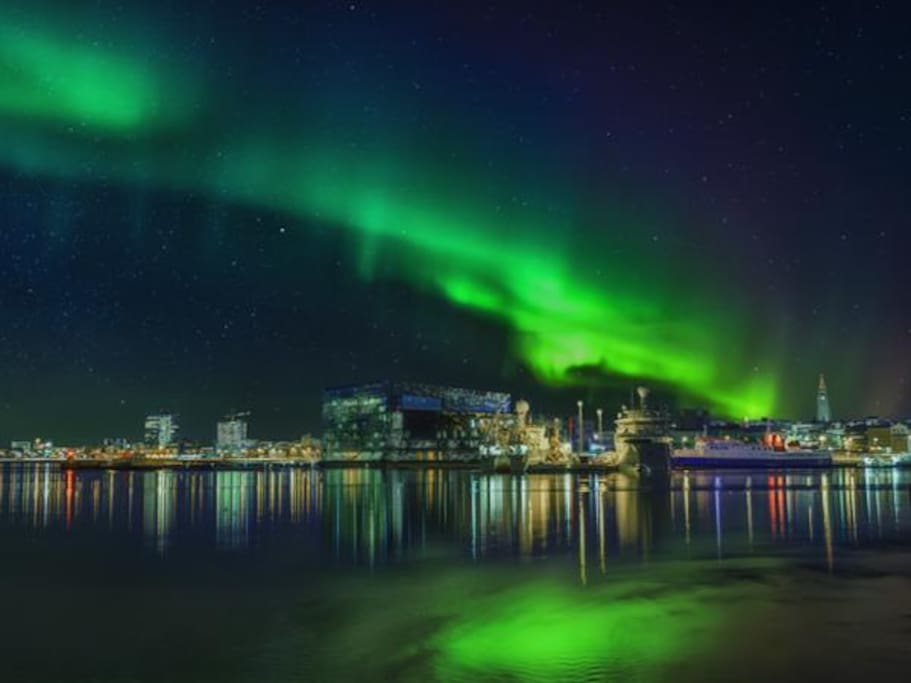 Northern lights dancing above Reykjavík city at night