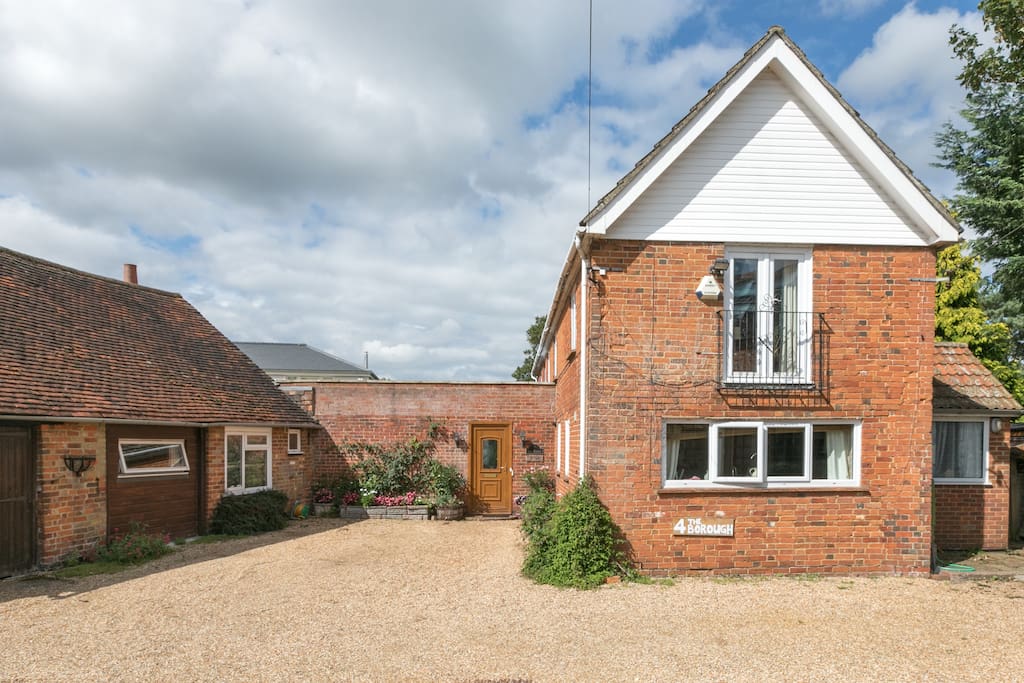 View of the whole house, from the driveway, showing the guest annex on the left and plenty of car parking space.