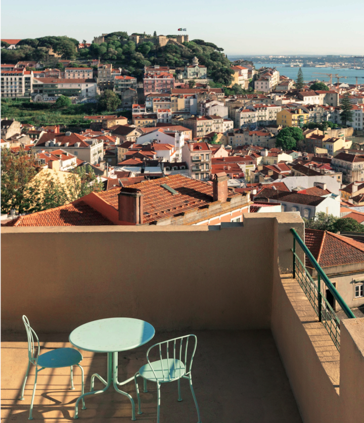 A veranda high in the hills in Lisbon overlooking the bustling streets and terracotta roofs with a gorgeous view of the seaside port below.