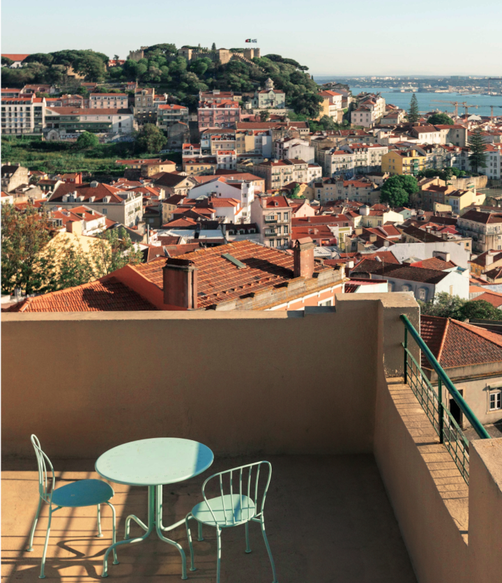 Une véranda dans les hauteurs de Lisbonne surplombe les rues animées et les toits aux tuiles rouges, et offre une vue magnifique sur le port maritime en contrebas.