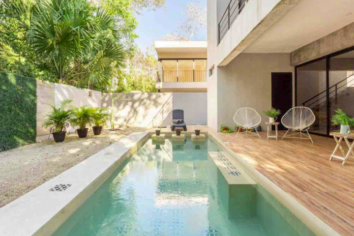 A modern escape in Mexico’s Playa Del Carmen. White angular walls and an outstretched pool sit shaded by nearby palms. Insulated like a fortress built for privacy and security, this sun-kissed getaway is a paradisiacal retreat in the heart of the city.