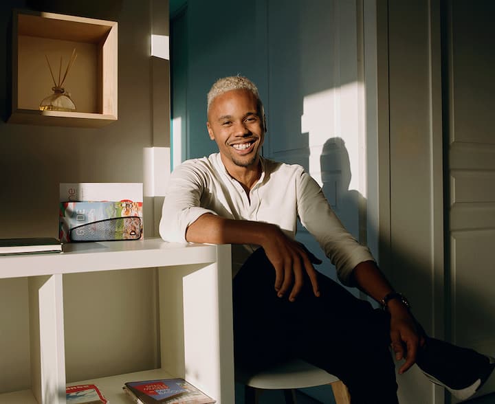 Photo of a Superhost sat on a chair in his home, smiling at the camera.