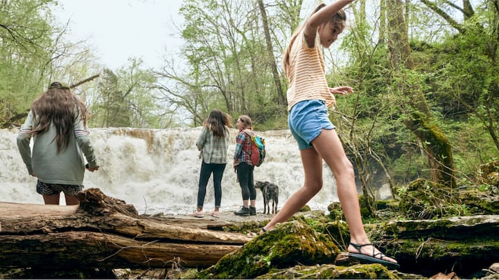 A group of children play near a miniature waterfall.