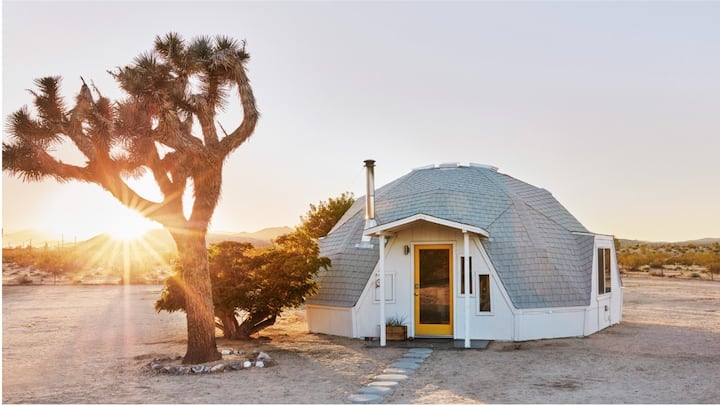 Sunrise over a white-domed cabin in the desert.