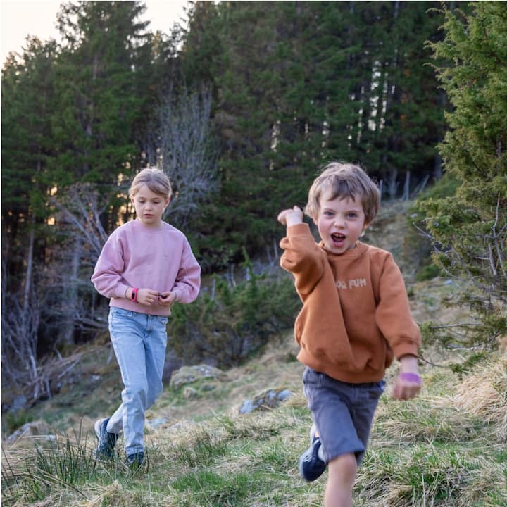 Two young kids playing on a mountain trail.