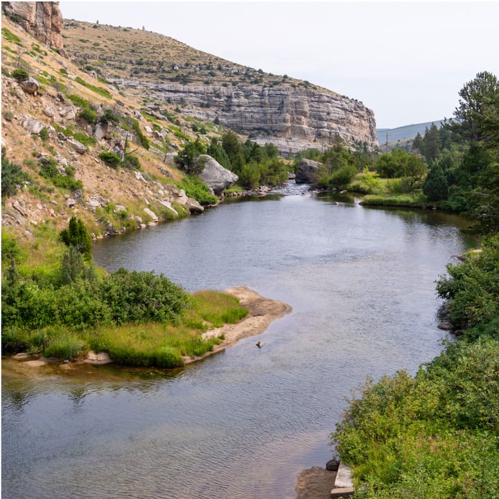 A wide river running through a gorge with grassy banks. 