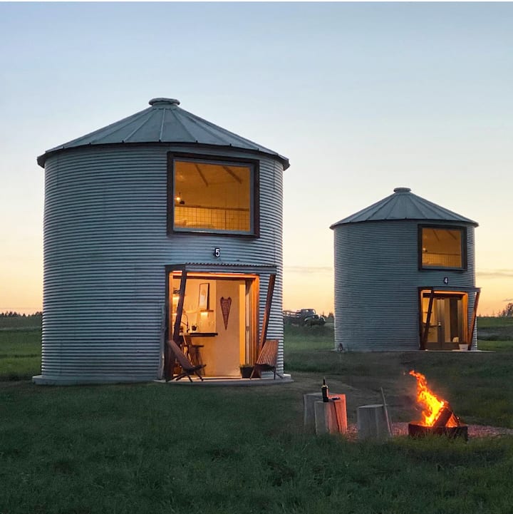 Two converted grain silos at dusk that are now modern Airbnbs.