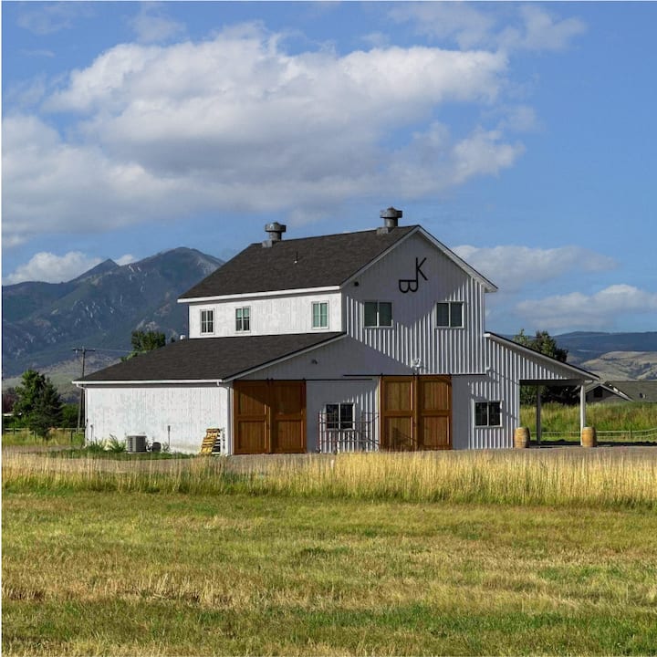 A two-story white farm house in front of a distant mountain range.