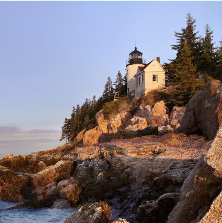A lighthouse at sunset on the rocky coast of Acadia, ME.