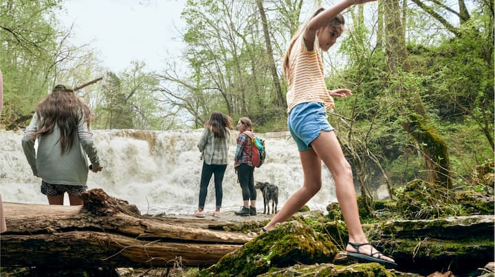 A group of children play near a miniature waterfall.