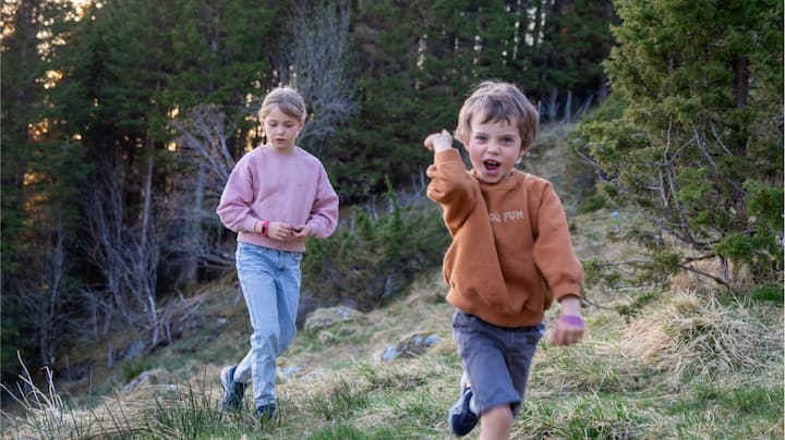 Two young kids playing on a mountain trail.
