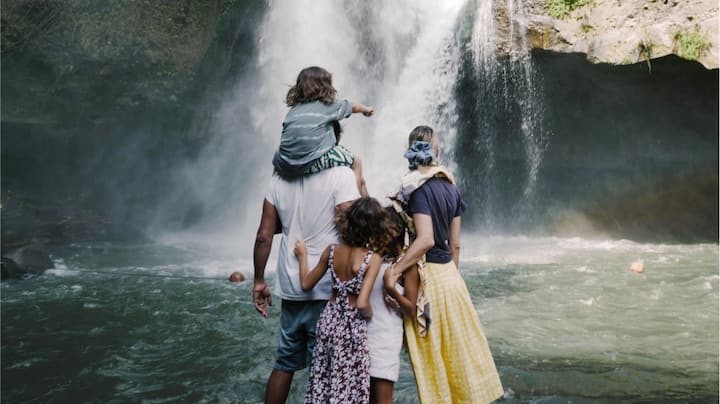 A young family takes in the grandeur of a massive waterfall.