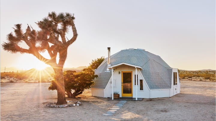 Sunrise over a white-domed cabin in the desert.