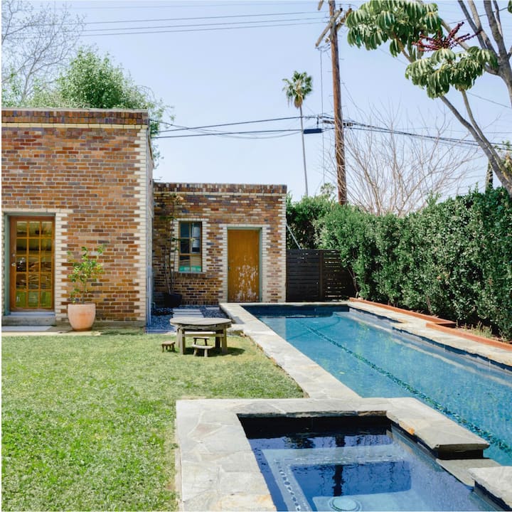 The backyard of a single-story brick house with a lap pool and hot tub.