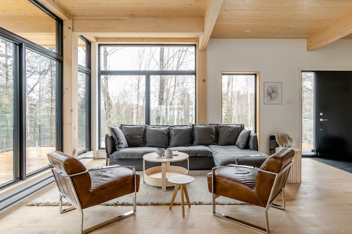 Een woonkamer in een houten huisje met een vriendelijk ogend houten plafond.